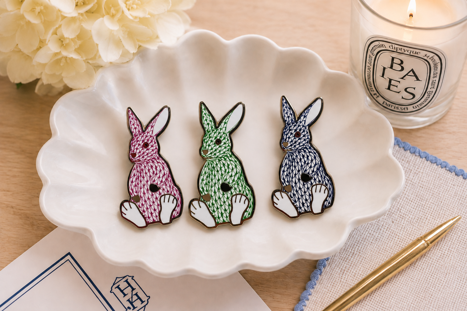 The Palm Bunny trio on a white scalloped dish with flowers, a candle and needlepoint