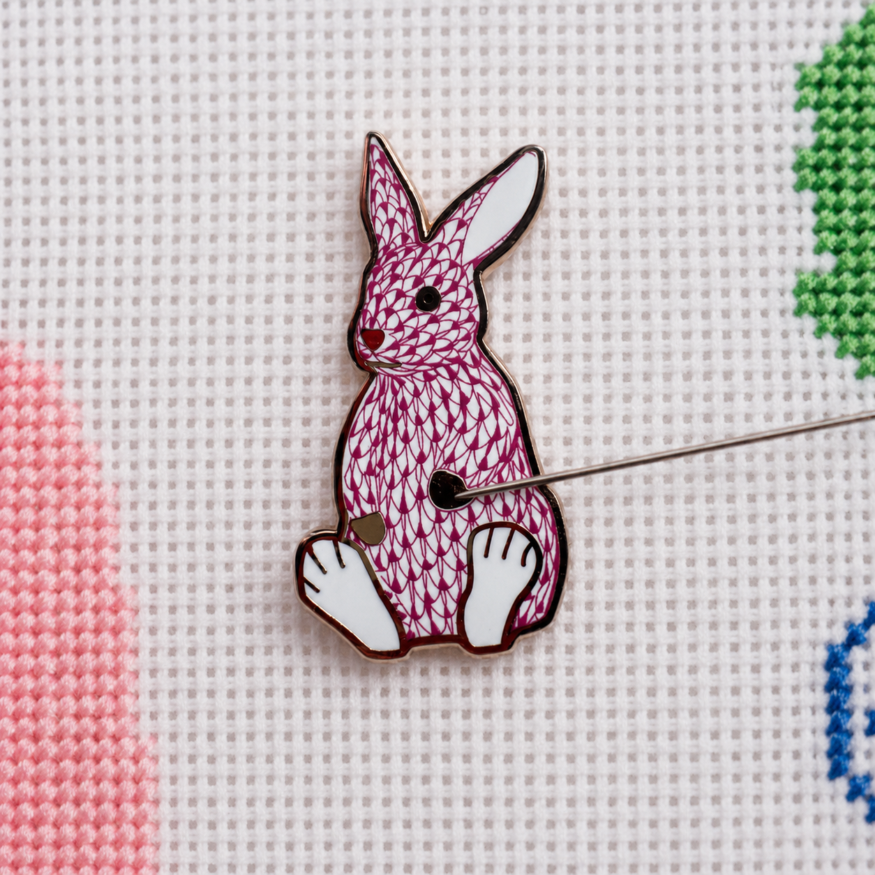 Palm Bunny Pink needle minder resting on needlepoint canvas